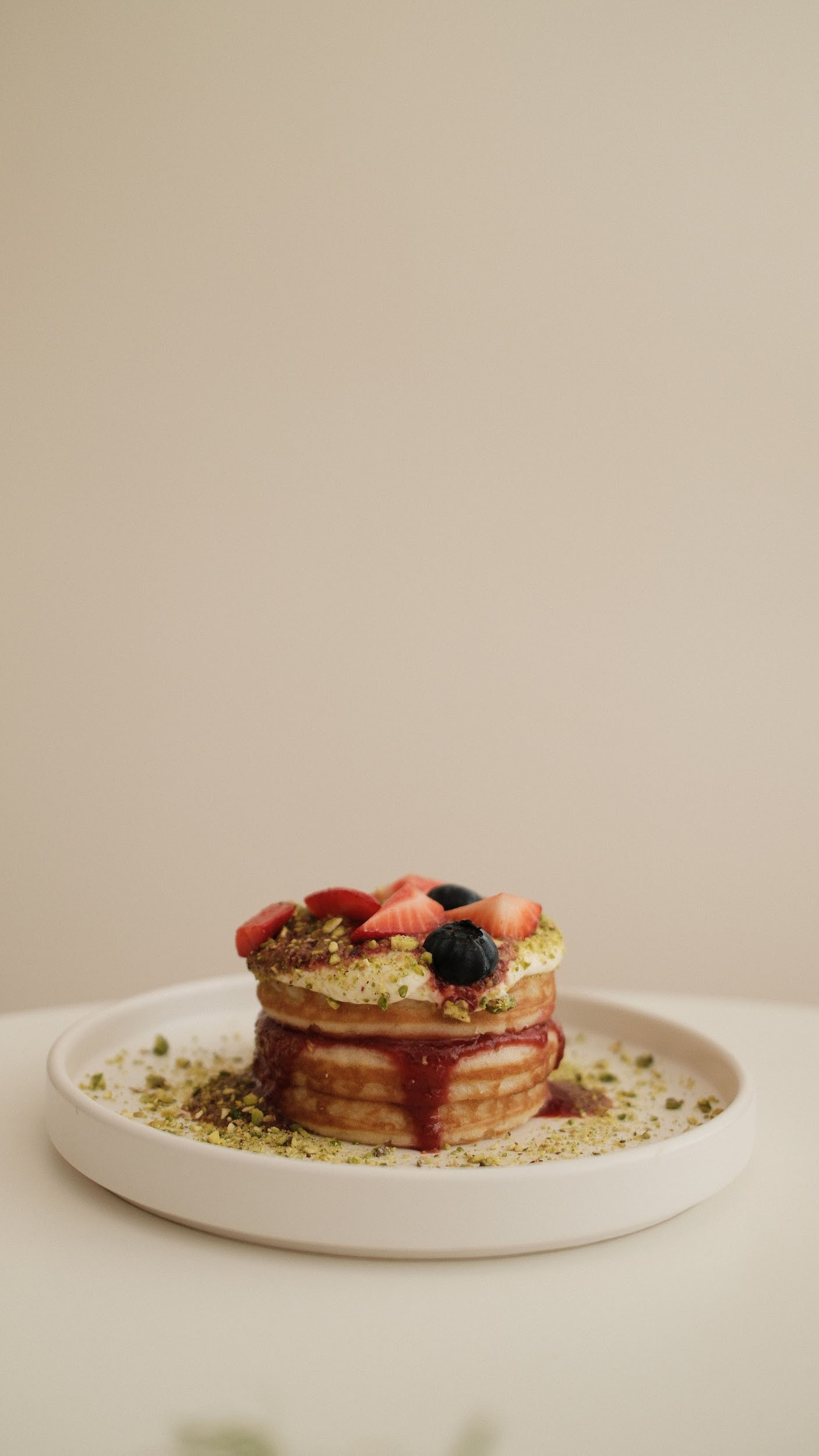 pancakes with cream and berries on a white plate